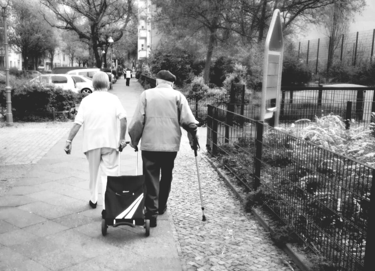 two people walking down a sidewalk pulling a cart