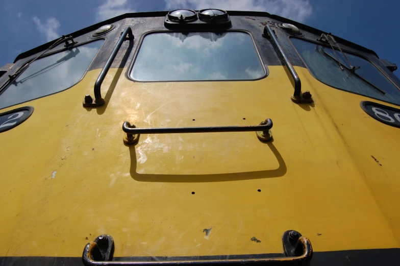 the bottom corner of an old train, that is yellow with some black trim