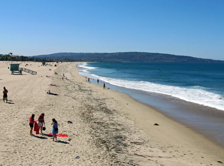 several people are on the beach playing with a kite