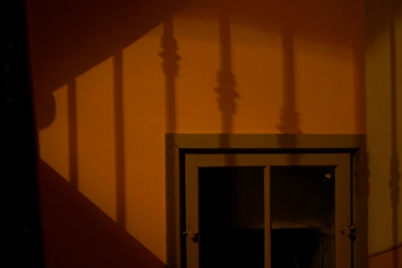 the shadow of a door is seen on the wall