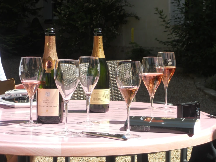 several bottles and six glasses on an outdoor table