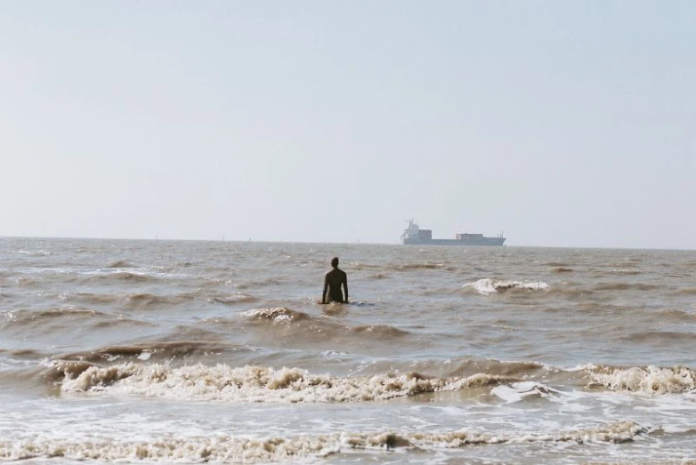 a person standing in the middle of the ocean with a boat nearby