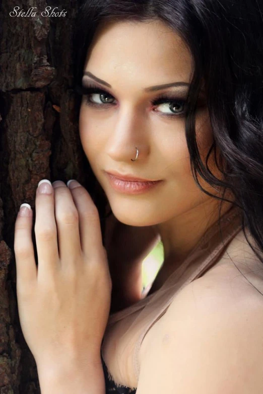 a beautiful young lady with an open  standing by a tree