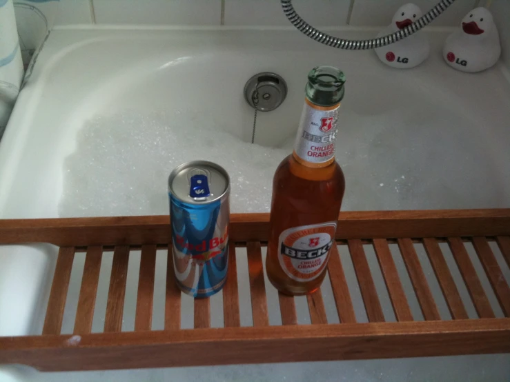 two cans of beer sitting on the edge of a bathtub