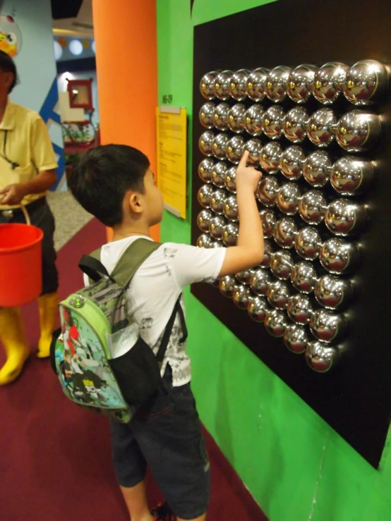 a small child is picking up magnets on a wall