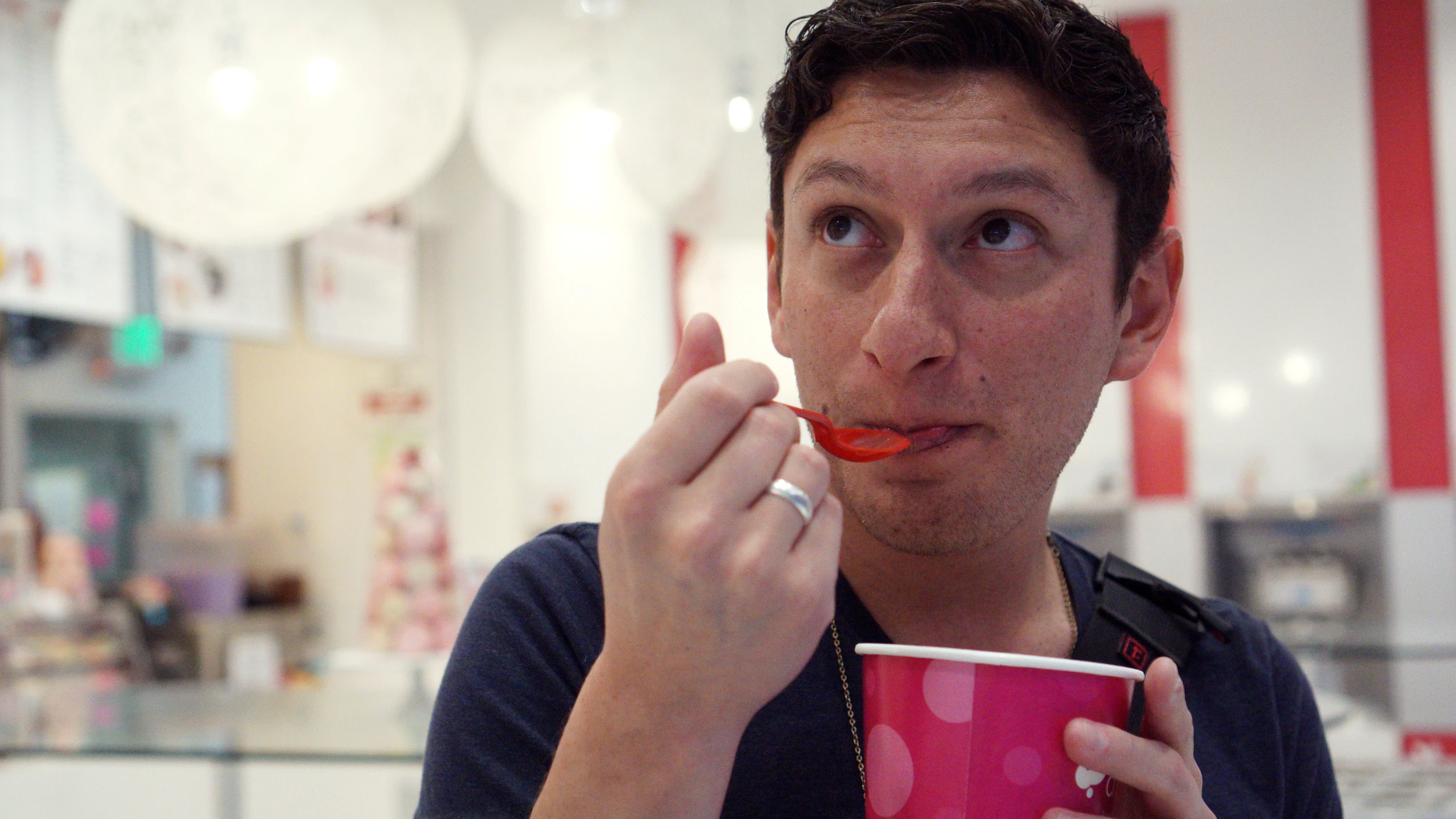 a man eating soing out of a pink cup