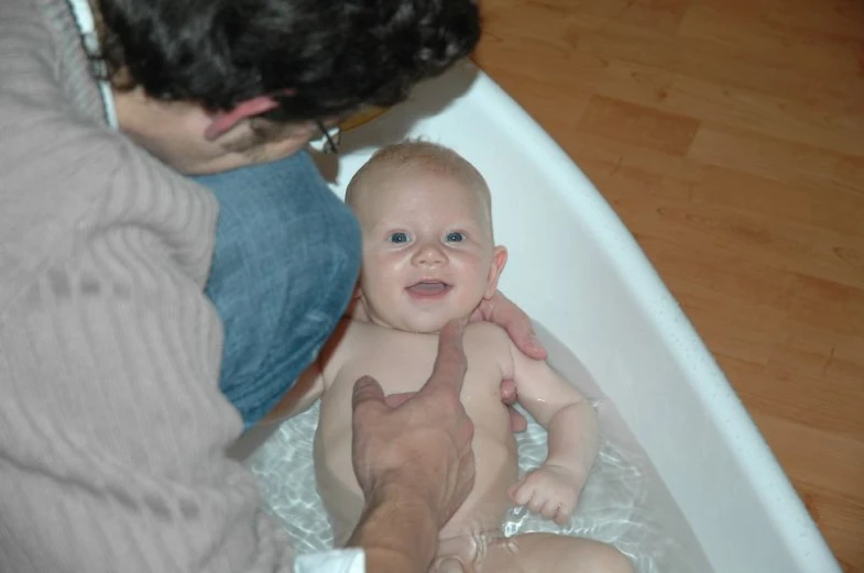 there is a man holding his baby in the bath tub