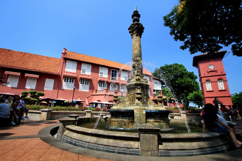 people sitting on a bench in front of an old town fountain