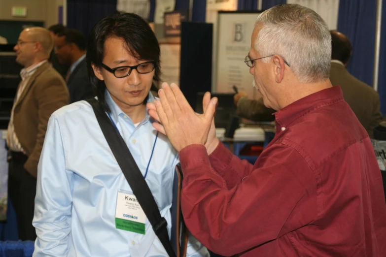 a man is speaking to another man at a business event