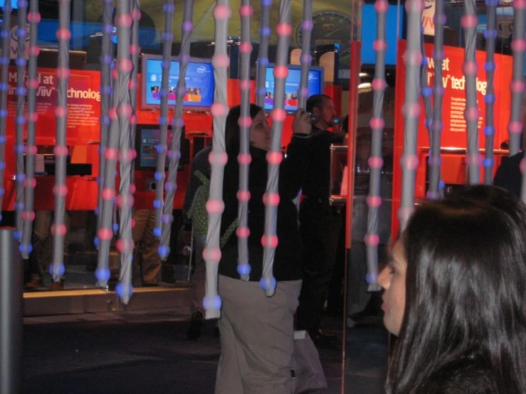 two people walk past an exhibit with colorful wires