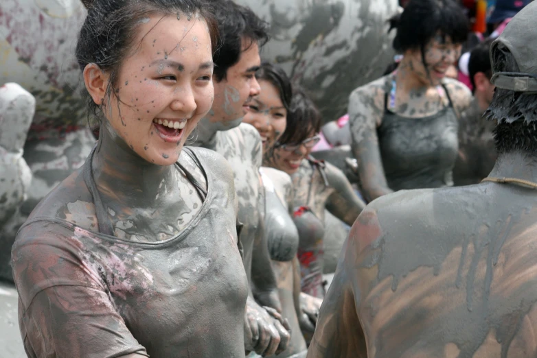 a woman is covered in mud walking past men