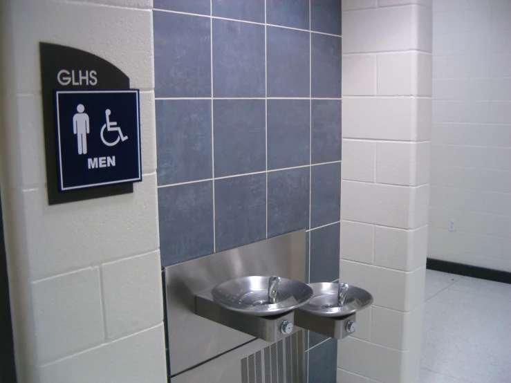 the restroom has two urinals mounted on the wall