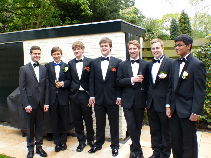 a group of men standing in suits in front of a white wall