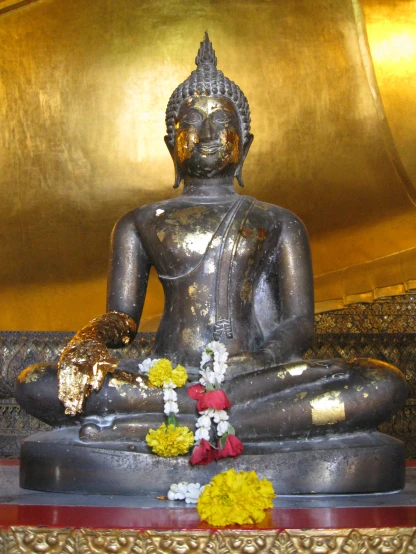 a buddha statue is adorned with yellow flowers