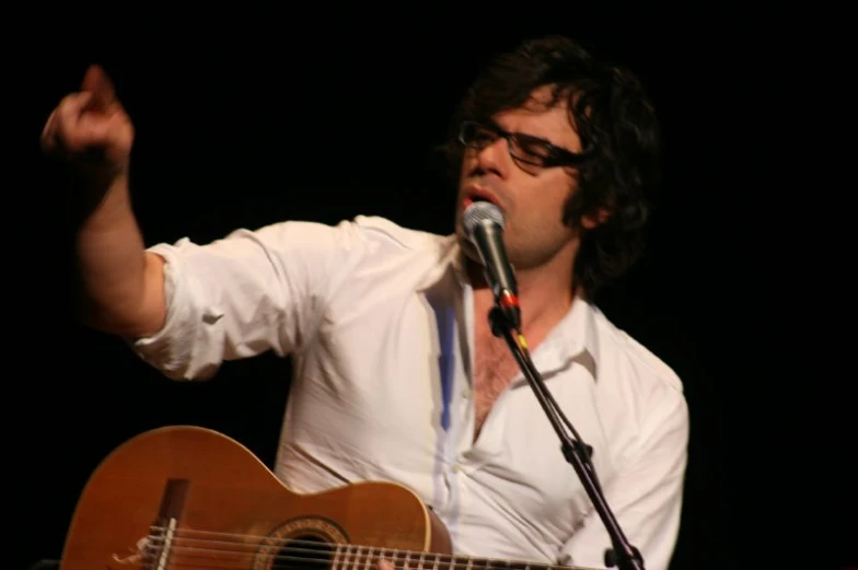 a man playing the guitar in front of a microphone