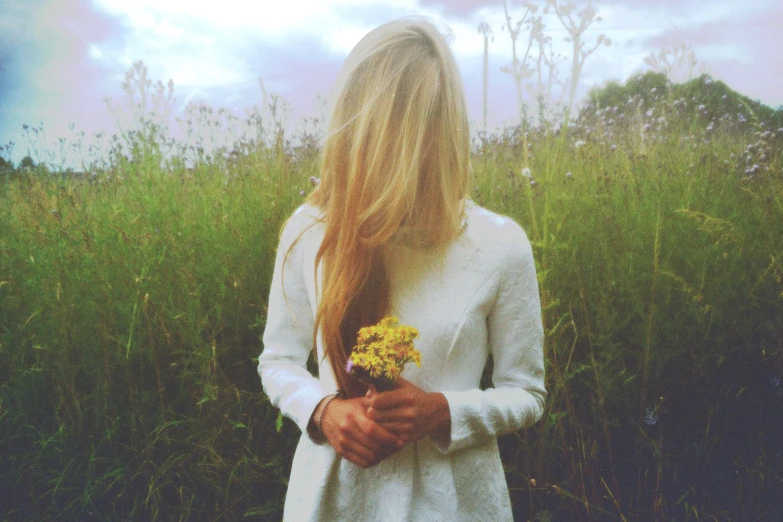 there is a woman standing in a field with flowers in her hands