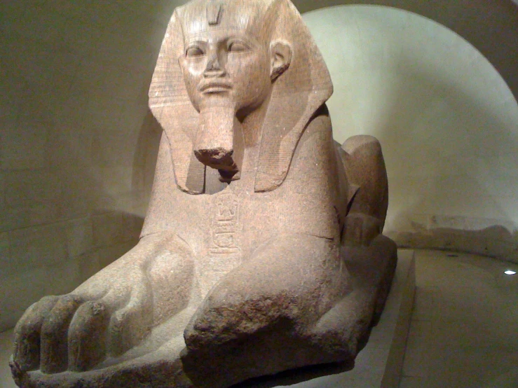 a large stone statue of an egyptian queen sitting on top of a desk