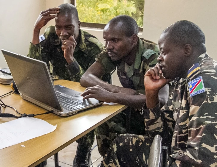 four people are sitting at a table with a laptop