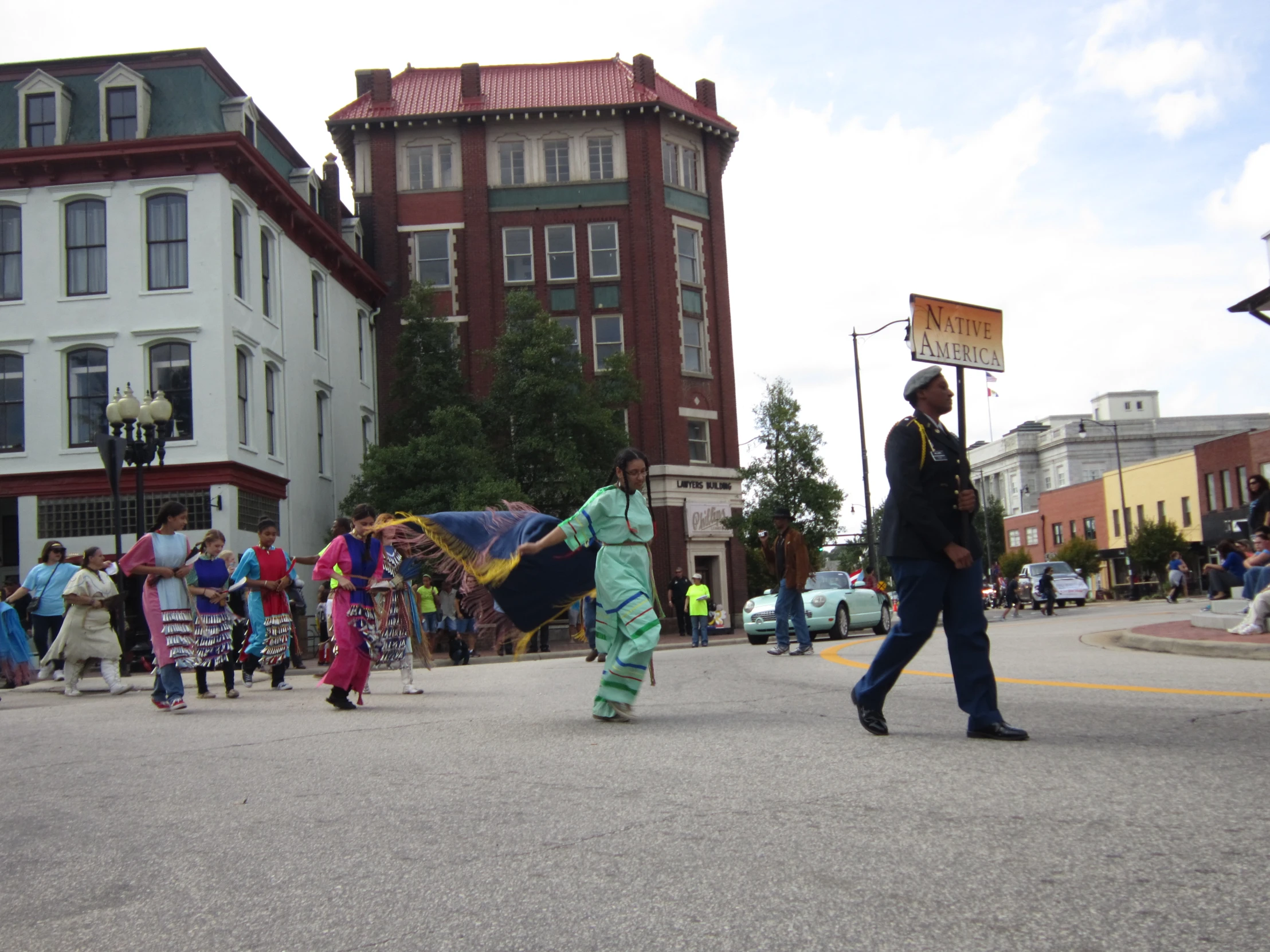 a group of people walking down a street under a cloudy blue sky