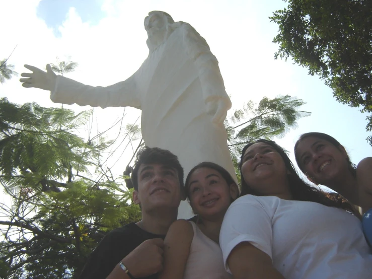 four people posing for a po next to the famous jesus statue