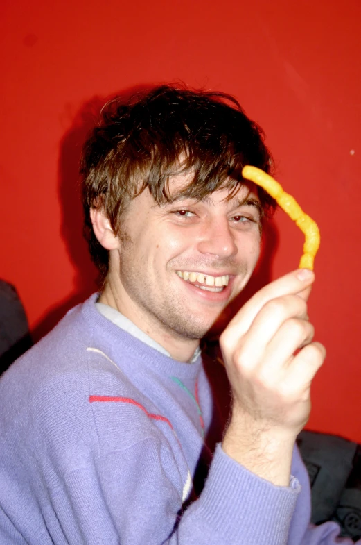 a man wearing a blue sweater holds a piece of food