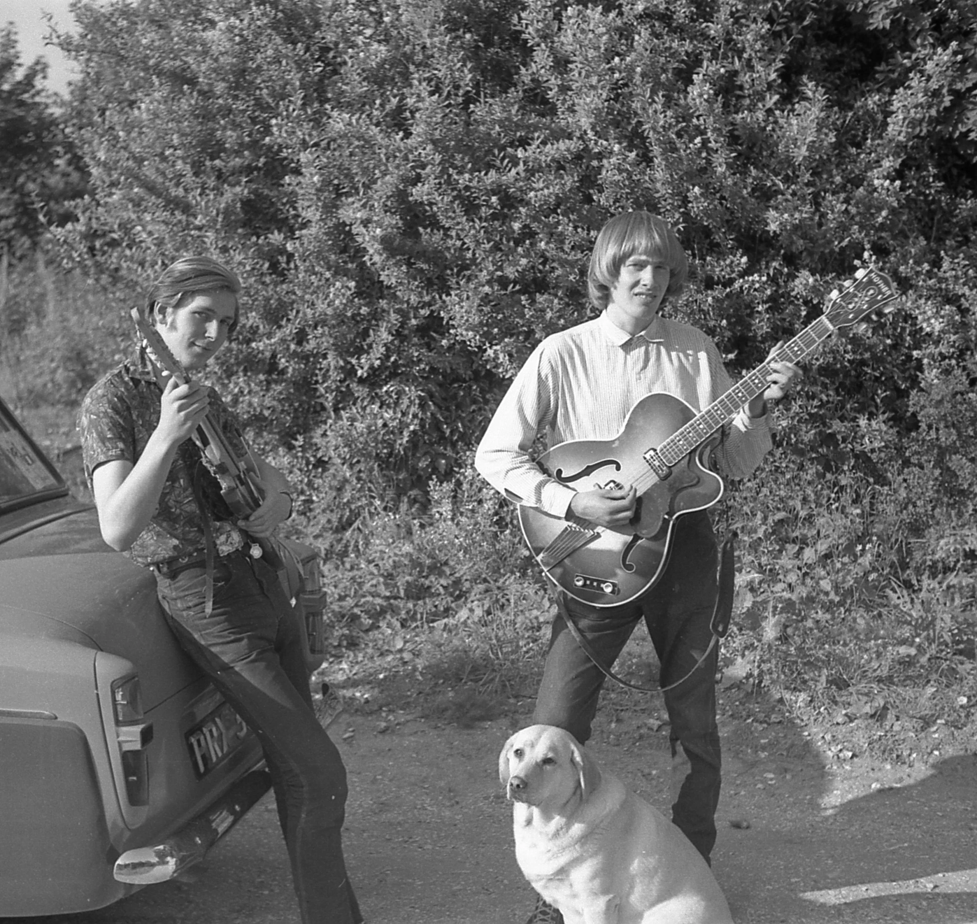 a couple of people standing around with guitar and a dog