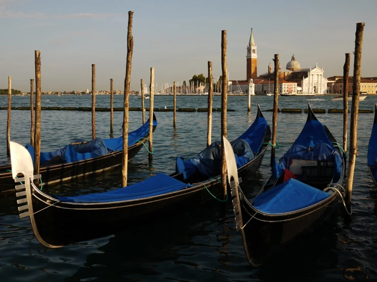 several gondolas are tied to poles in the water