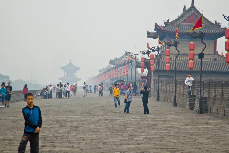 people standing near some stone walls and red lanterns