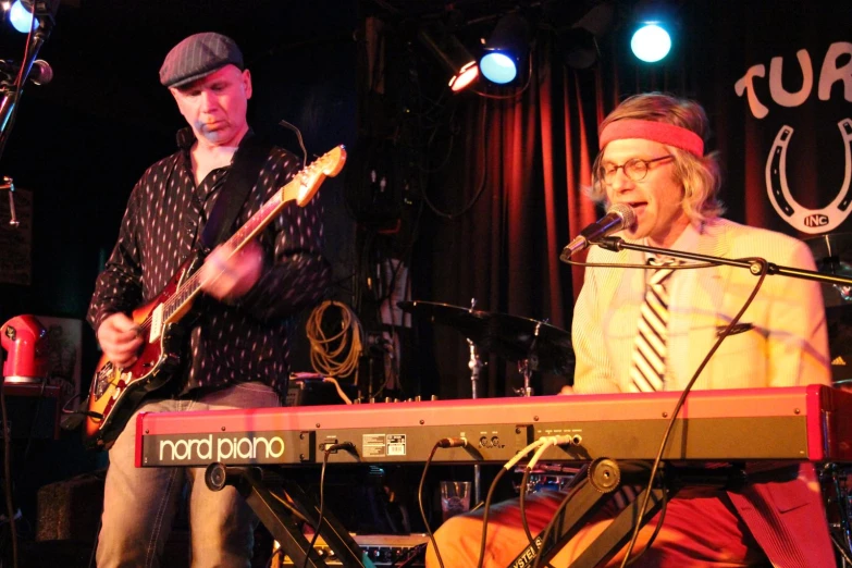 a man standing in front of a keyboard while playing an electric guitar