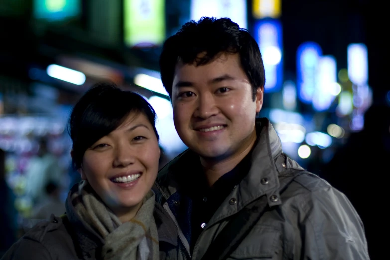 two people smile as they pose in front of a night scene