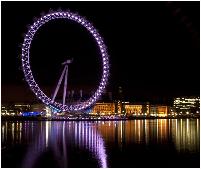 an enormous, illuminated ferris wheel is in the city