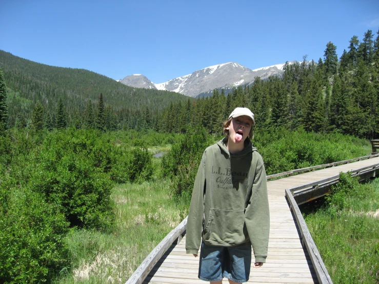 a young man is standing on a boardwalk near the woods