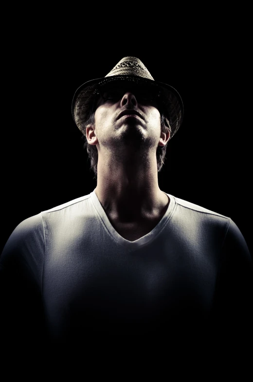 man in white shirt and hat in dark background