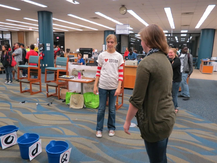 some students and staff standing by tables with plastic buckets in the middle