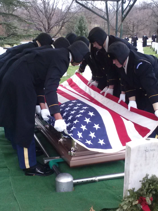 the sailors place the flag on the gravestone