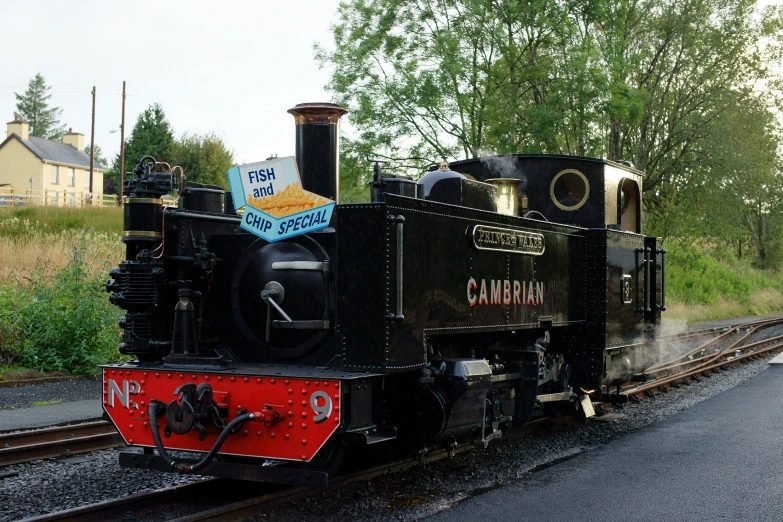 an old black train on railroad tracks in rural area