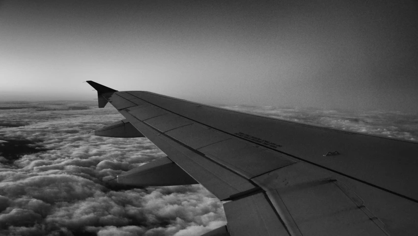 a airplane's wing with some clouds and sky