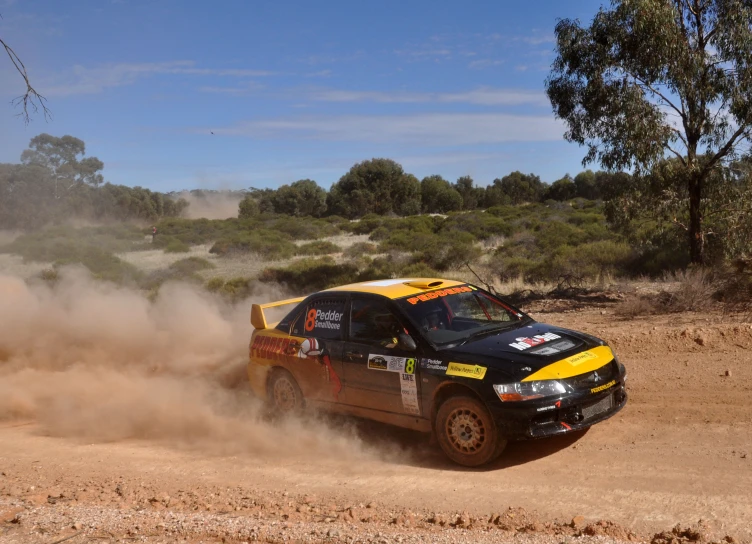 a black and yellow truck driving on a dusty road