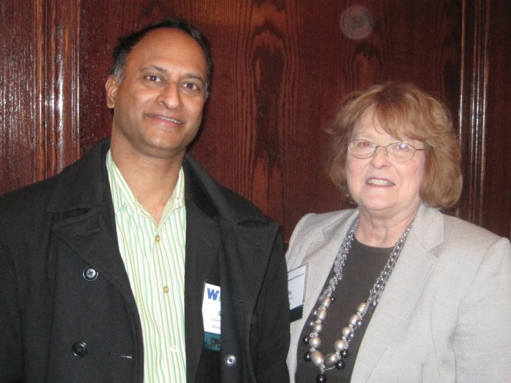 a man in a business suit standing next to an older woman