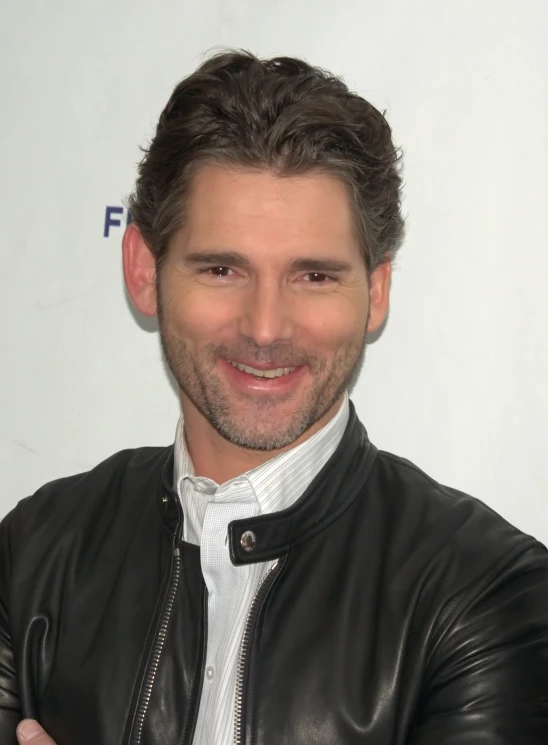 a young man smiling for the camera in his leather jacket