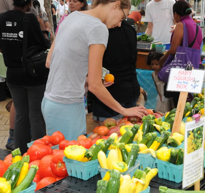 woman standing in front of a vegetable stand at a market