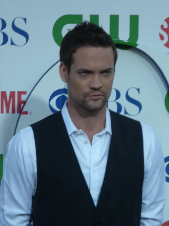 a young man in a white shirt and vest posing for a po