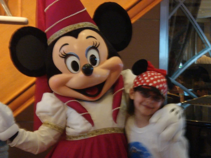 a woman standing next to mickey mouse at a convention