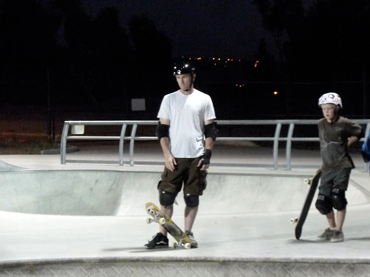 a young man skateboarding at night, while two others watch