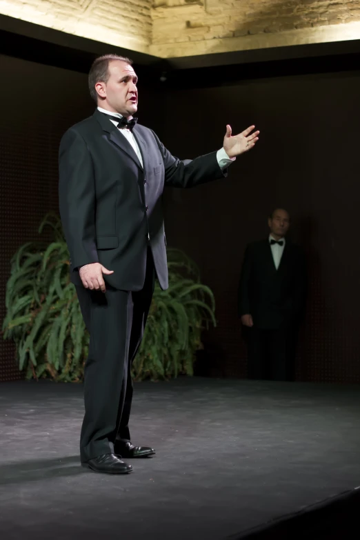 man dressed in tuxedo giving a presentation to people