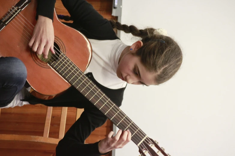 a woman is holding a guitar while sitting down