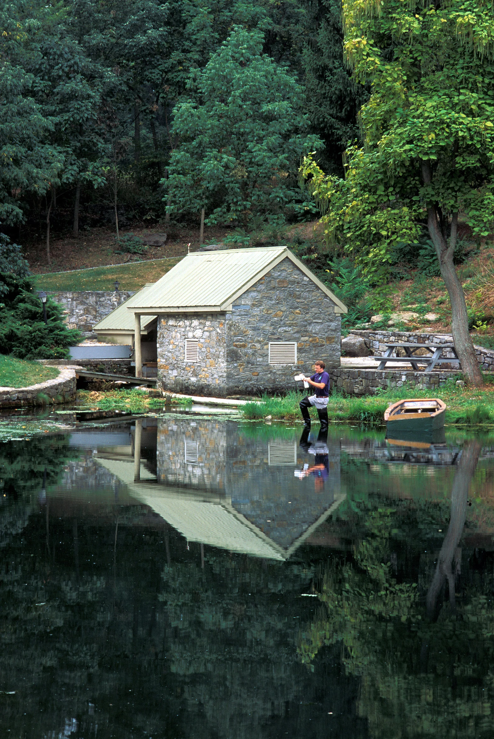 a couple standing on the edge of a lake next to a boat