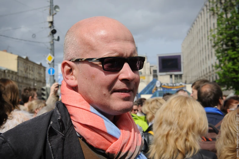 a man in glasses and a scarf in the middle of the crowd