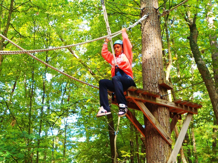 girl on the ropes in the trees with a camera