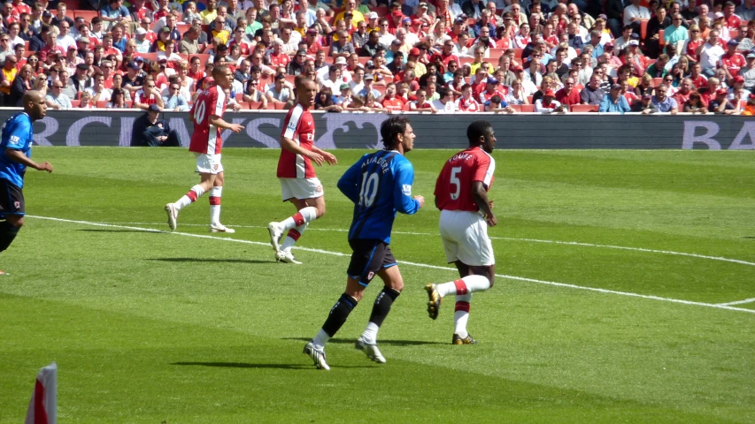 soccer players play on an athletic field in front of a crowd